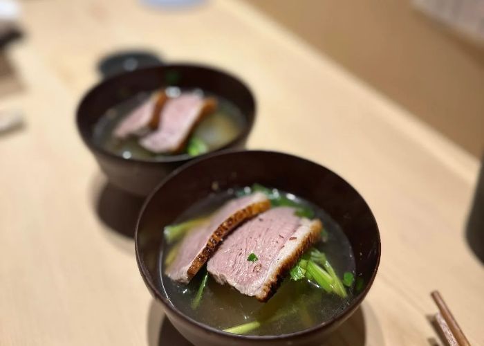 Two dishes being served at Washokuya Taichi. It appears to be grilled meat served in a flavorful broth.
